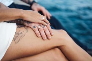 una pareja joven está sentada en el muelle junto al mar foto