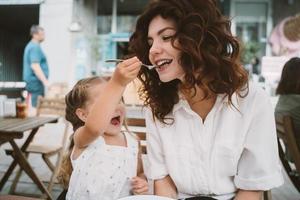 mamá joven comiendo pastel con un niño sonriente en la calle foto