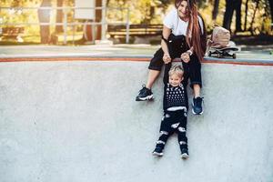 Beautiful young hipster mom holds her little son by the hands photo