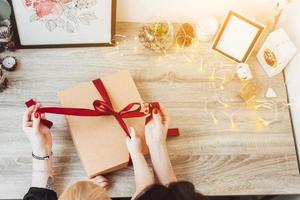 Woman wrapping present in paper with red ribbon. photo