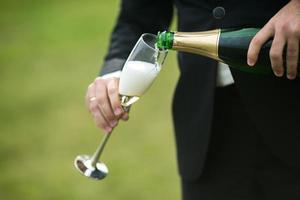 Groom pours a glass of champagne photo