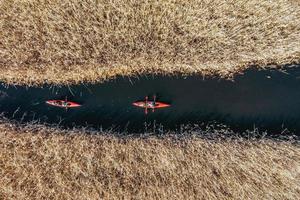 Group of people in kayaks among reeds on the autumn river. photo