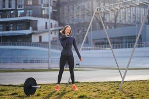 Young woman exercising with a kettlebell outside at stadium photo