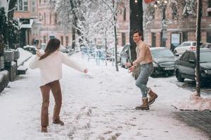 Joyful young couple is playing snowballs at the street. photo