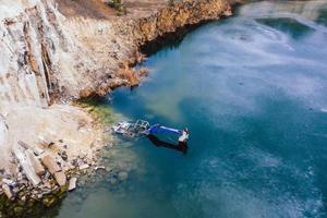 Flooded excavator in a large lake near the basaltic quarry photo