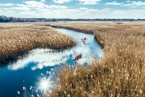 Group of people in kayaks among reeds on the autumn river. photo