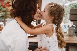 retrato de una pequeña hija besando a su hermosa y feliz madre foto