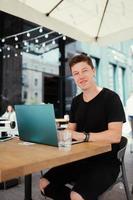 Portrait of man sitting at a table working on a laptop computer. photo