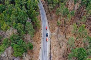 Several cars with kayaks on roof rack driving on the road among trees photo