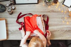 mujer envolviendo presente en papel con cinta roja. foto