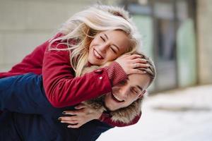 Young handsome guy giving girlfirend piggyback ride photo