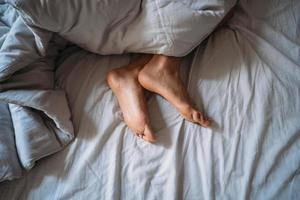 Close-up woman feet alone in white bed photo