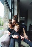 mamá y dos hijas juntas en la ventana foto