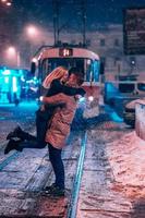 pareja de adultos jóvenes en la línea de tranvía cubierta de nieve foto