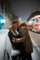 Young adult couple kissing each other on snow covered street photo