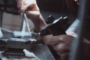 In the workshop, a woman jeweler is busy soldering jewelry photo