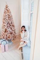 Young woman in an elegant dress near the Christmas tree photo