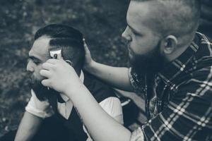 barber shaves a bearded man in vintage atmosphere photo