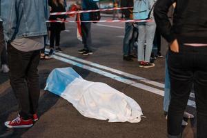 cuerpo humano cubierto por una sábana tirada en la calle. foto