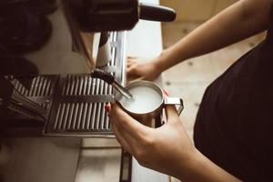 el barista está haciendo leche hervida. él usa una máquina de café especial para ello. foto