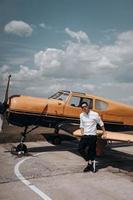 A man standing on the background of a small single engine plane. photo