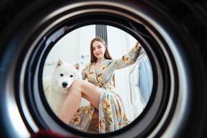 Young woman at home puts the dress in the drying machine. photo