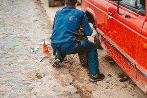 el hombre cambia la rueda manualmente en un camión todoterreno 4x4 foto