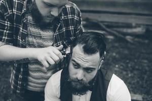barber shaves a bearded man in vintage atmosphere photo