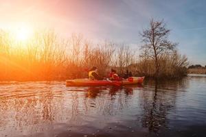 Group of people in kayaks among reeds on the autumn river. photo