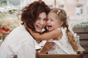 Cute little girl and her beautiful young mom hug each other photo