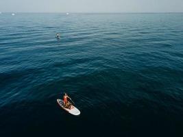 Mother with two daughters stand up on a paddle board photo