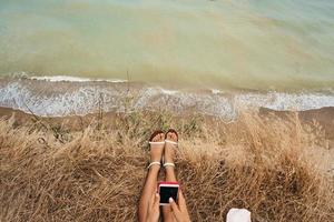 beautiful young girl sitting and holding a smartphone in her hands, top view photo