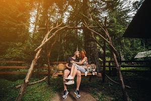 beautiful couple together with dog on a swing photo