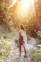 Beautiful, young girl walks at the foot of the mountain along photo