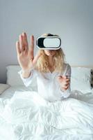 niña sentada en una cama con auriculares vr foto