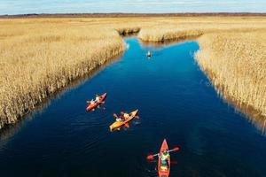 Group of people in kayaks among reeds on the autumn river. photo