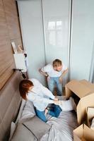 papá, mamá y su hijo pequeño juegan en el dormitorio con cajas de papel foto