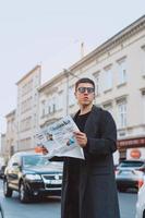hombre inteligente en gafas de sol con papel en la calle foto