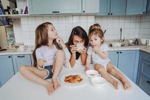 Mom and two daughters eat pancakes photo