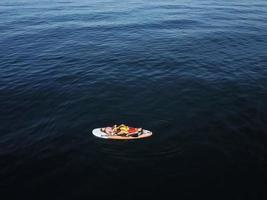 Mother with two daughters stand up on a paddle board photo