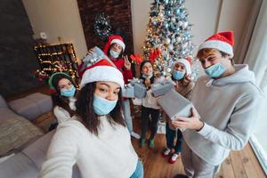 Multiethnic group of friends in Santa hats with gifts in hands. photo