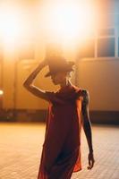 The young, attractive girl in a hat poses to the camera at night photo