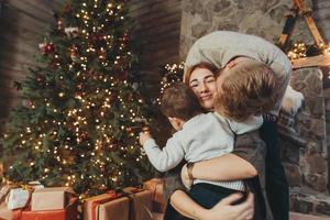 Young caucasian family mom dad son near fireplace christmas tree photo