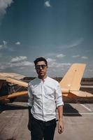 A man standing on the background of a small single engine plane. photo