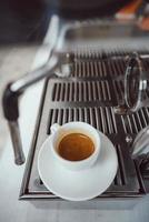 close-up view of glass cup with cappuccino and coffee machine photo