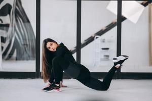 mujer joven con traje deportivo negro haciendo pose de yoga en el interior. foto