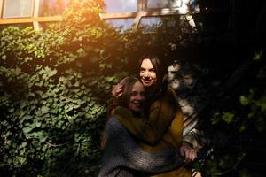 Two girls hugging in the shade of of leaves photo