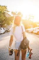 Young girl with a skateboard on a car park. photo