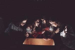 Sisters opens a box with a Christmas present and fascinated looks inside photo