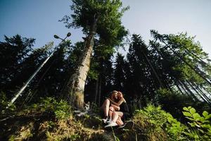 beautiful couple sitting in a forest near the tree photo